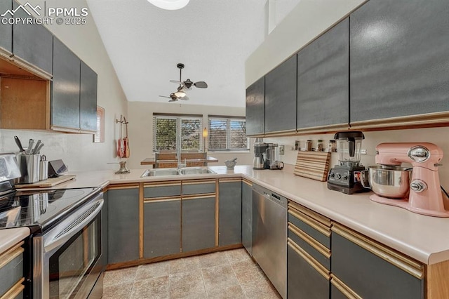 kitchen with ceiling fan, appliances with stainless steel finishes, vaulted ceiling, light countertops, and a sink