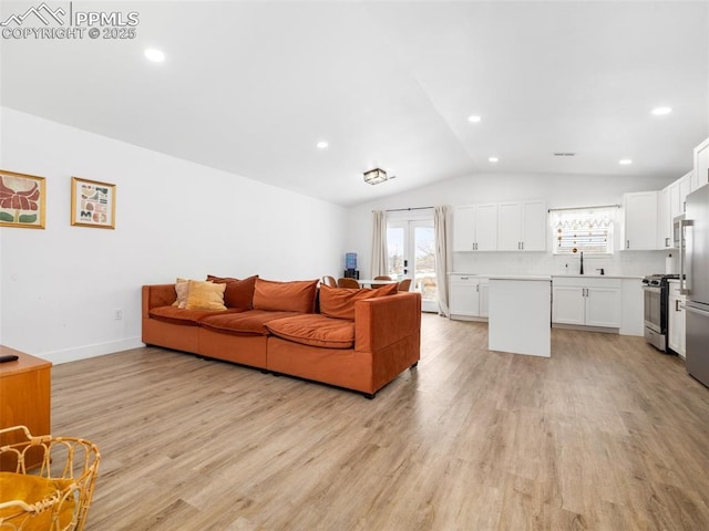 living room with sink, lofted ceiling, and light hardwood / wood-style floors