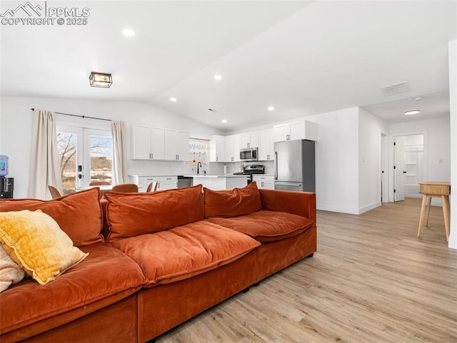 living room featuring sink, vaulted ceiling, french doors, and light wood-type flooring