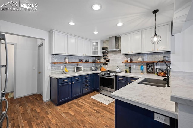 kitchen featuring pendant lighting, wall chimney range hood, appliances with stainless steel finishes, white cabinets, and blue cabinets