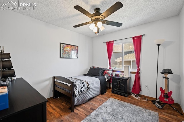 bedroom with ceiling fan, a textured ceiling, and dark hardwood / wood-style flooring