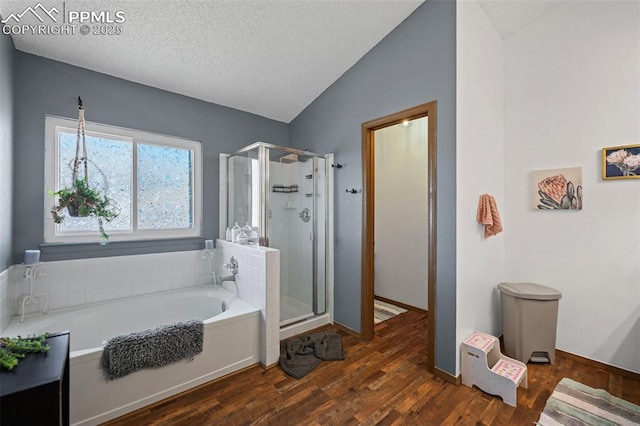 bathroom with hardwood / wood-style floors, vaulted ceiling, plus walk in shower, and a textured ceiling