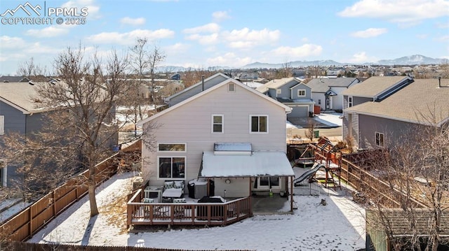 snow covered back of property with a deck with mountain view