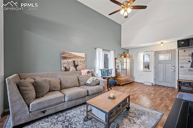 living room with dark wood-type flooring, ceiling fan, and high vaulted ceiling