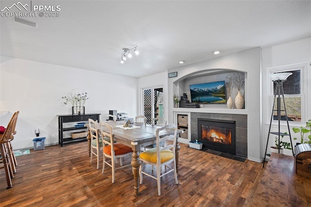 dining space featuring a tile fireplace and dark wood-type flooring