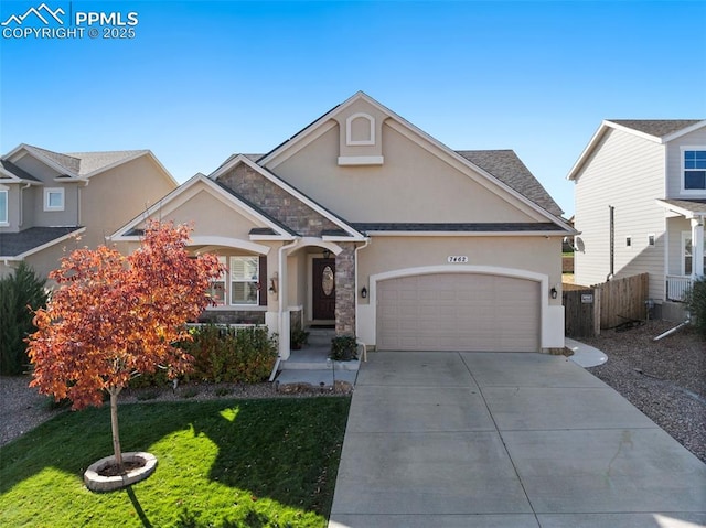 view of front of home with a garage, fence, driveway, stone siding, and stucco siding