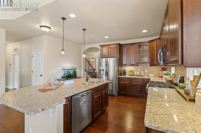 kitchen featuring tasteful backsplash, arched walkways, dark wood-style flooring, light stone countertops, and stainless steel appliances