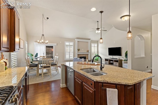 kitchen featuring a fireplace, appliances with stainless steel finishes, open floor plan, a sink, and vaulted ceiling