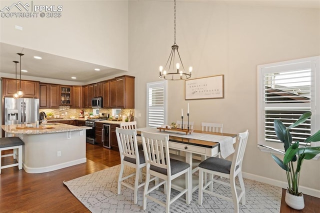 dining room featuring recessed lighting, a towering ceiling, baseboards, dark wood finished floors, and an inviting chandelier