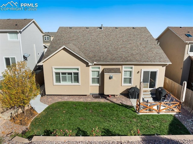 back of house featuring roof with shingles, a yard, stucco siding, entry steps, and fence