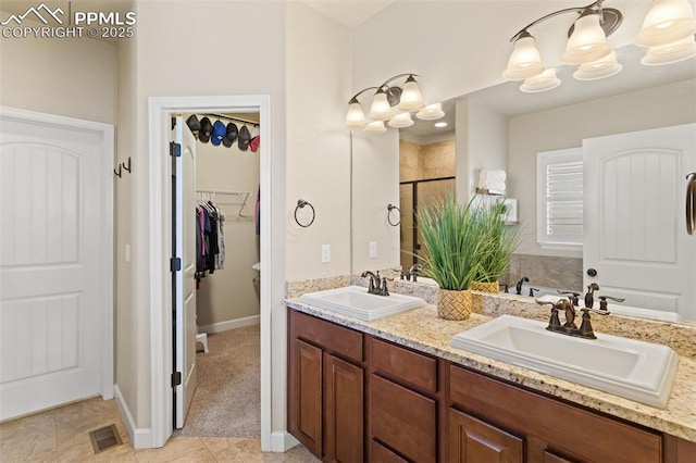 full bathroom with a spacious closet, double vanity, a sink, and visible vents