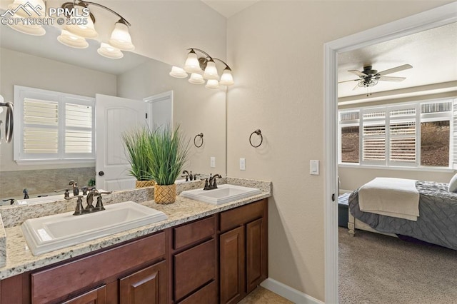 full bathroom featuring ceiling fan with notable chandelier, a sink, baseboards, and double vanity