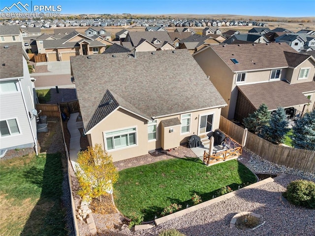 view of front facade featuring a fenced backyard, a residential view, a shingled roof, and a patio