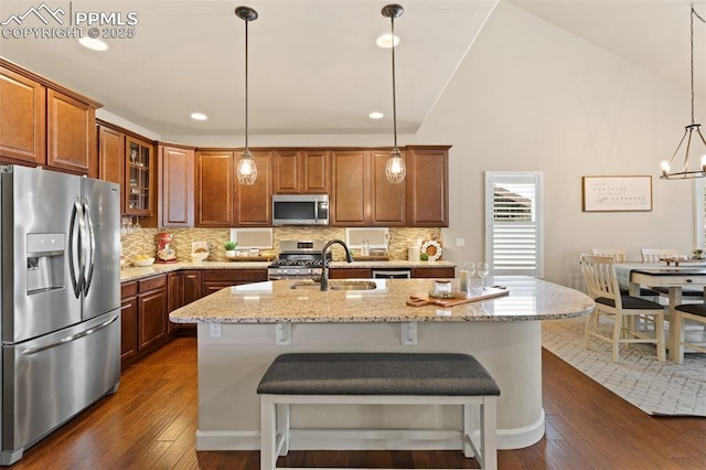 kitchen featuring an island with sink, backsplash, stainless steel appliances, and dark wood finished floors