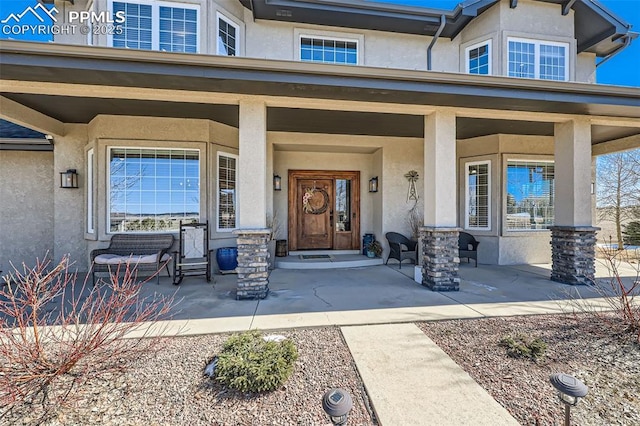 view of exterior entry with stucco siding and a porch