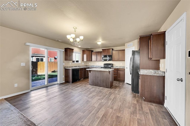 kitchen with a kitchen island, pendant lighting, wood-type flooring, a chandelier, and black appliances