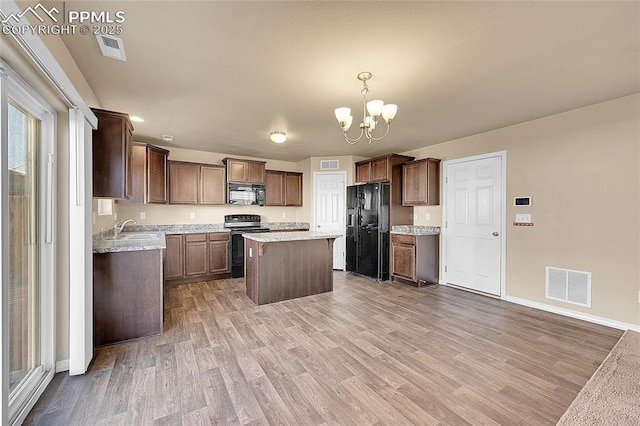 kitchen with an inviting chandelier, a center island, light hardwood / wood-style flooring, hanging light fixtures, and black appliances