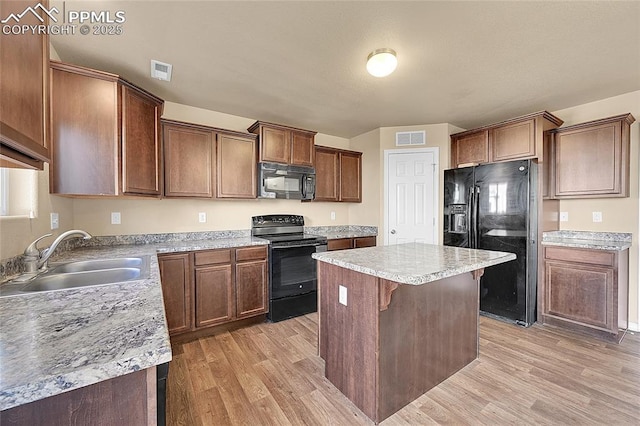 kitchen with light wood-type flooring, a center island, sink, and black appliances