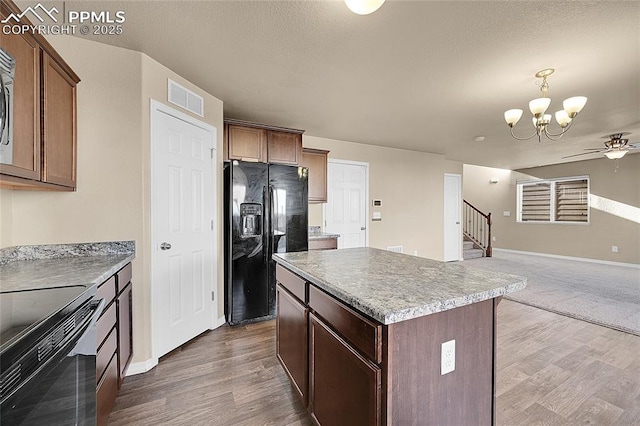 kitchen with black fridge, stainless steel electric range oven, dark hardwood / wood-style flooring, a kitchen island, and pendant lighting