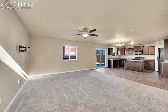 unfurnished living room with carpet flooring and ceiling fan with notable chandelier