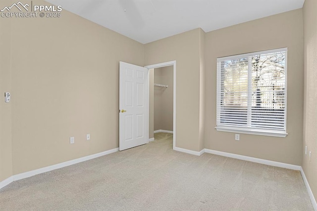 unfurnished bedroom featuring a spacious closet, light colored carpet, and a closet