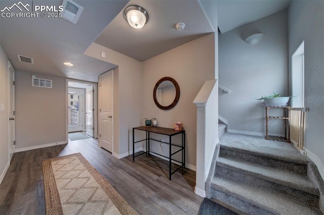 entryway with visible vents, stairway, wood finished floors, and baseboards