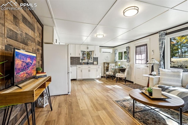 living room featuring sink, light hardwood / wood-style flooring, and an AC wall unit