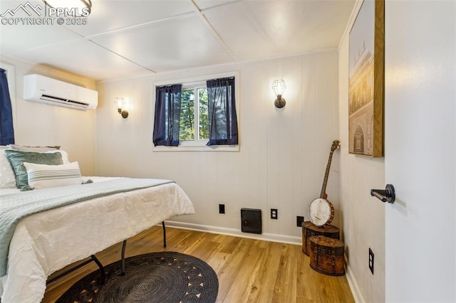 bedroom featuring a wall mounted AC and light hardwood / wood-style floors