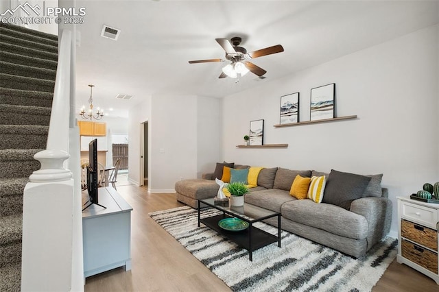 living room with wood-type flooring and ceiling fan with notable chandelier