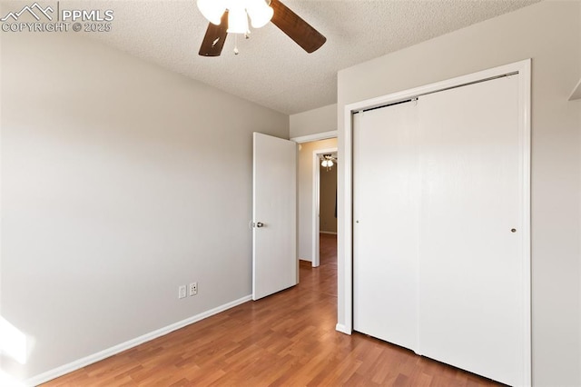 unfurnished bedroom featuring wood-type flooring, ceiling fan, a textured ceiling, and a closet