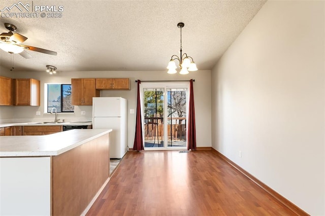 kitchen featuring ceiling fan with notable chandelier, decorative light fixtures, sink, white refrigerator, and light hardwood / wood-style floors