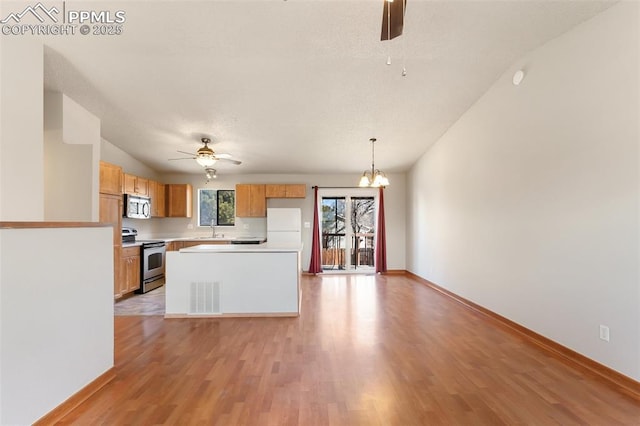 kitchen featuring ceiling fan with notable chandelier, sink, hanging light fixtures, stainless steel appliances, and light wood-type flooring