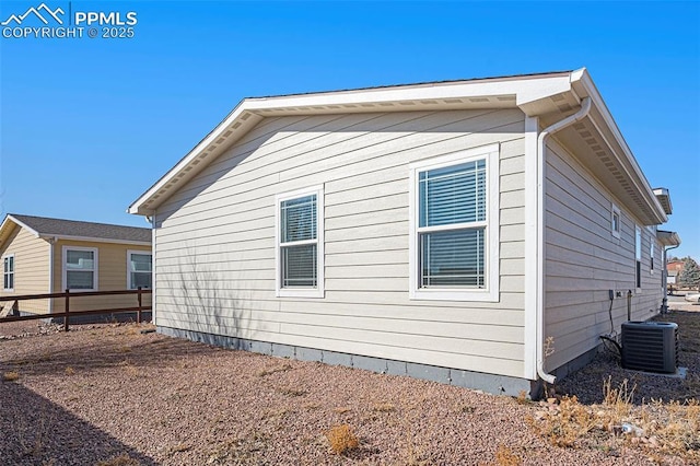 view of side of home featuring fence and central AC unit