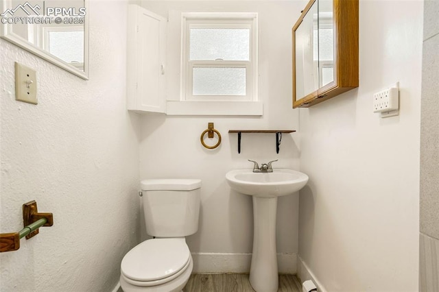 half bath featuring baseboards, a sink, and toilet