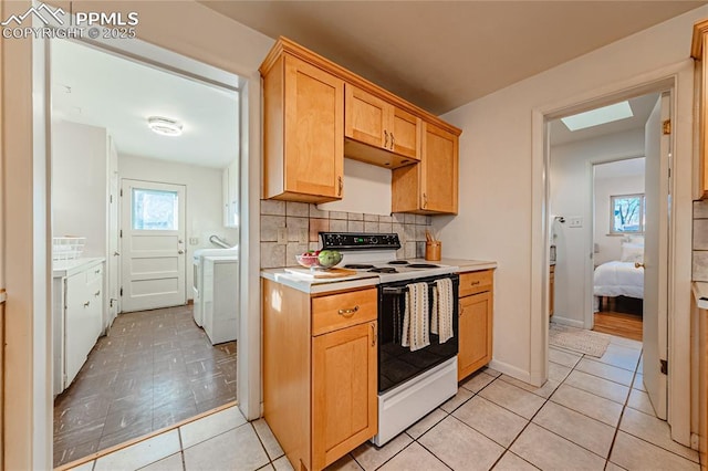 kitchen with tasteful backsplash, light tile patterned flooring, washer and dryer, and white range with electric stovetop