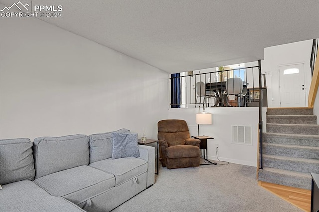 living area featuring stairway, baseboards, visible vents, and a textured ceiling