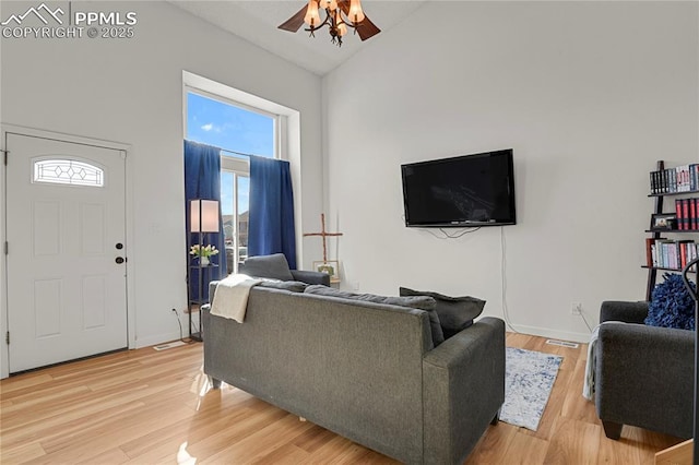 living area with baseboards, high vaulted ceiling, light wood-style flooring, and a ceiling fan