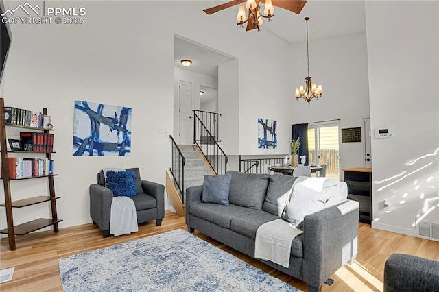 living area with light wood-style floors, baseboards, a high ceiling, and stairs