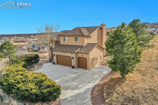 view of front of home featuring an attached garage, a tile roof, stone siding, driveway, and stucco siding