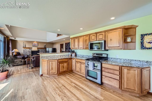 kitchen with a peninsula, light wood finished floors, appliances with stainless steel finishes, and light stone countertops