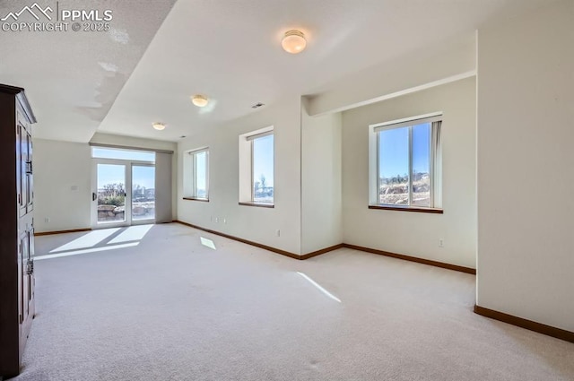 spare room with baseboards and light colored carpet