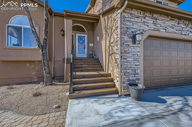 view of exterior entry featuring an attached garage and stone siding