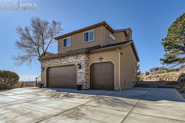 exterior space with stone siding, driveway, an attached garage, and stucco siding