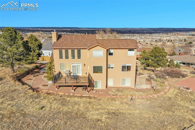 back of property with a chimney, a deck, and stucco siding