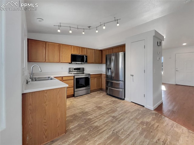 kitchen featuring rail lighting, appliances with stainless steel finishes, sink, and light hardwood / wood-style floors