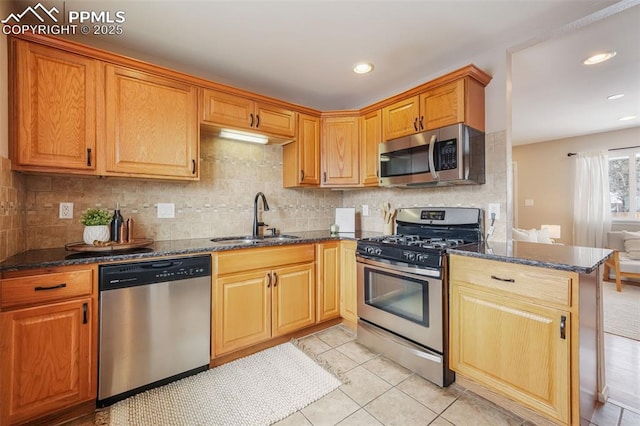 kitchen with backsplash, appliances with stainless steel finishes, sink, and dark stone counters