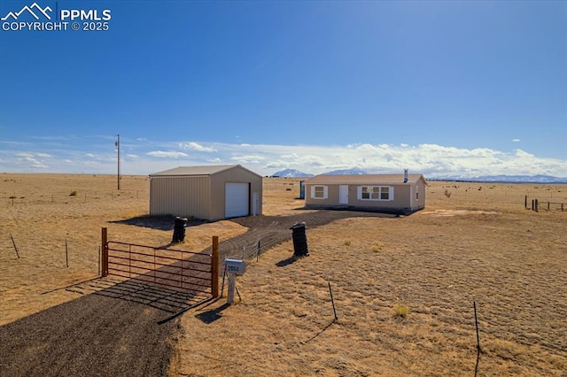 view of front facade featuring a rural view, fence, a detached garage, and an outdoor structure