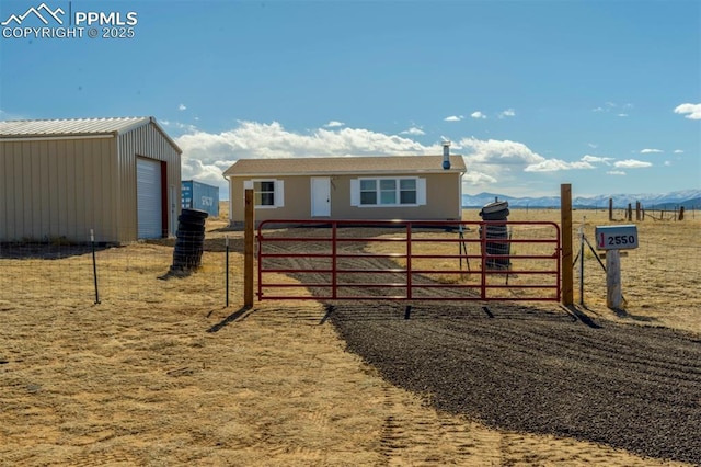 exterior space featuring an outbuilding, a rural view, fence, and a mountain view