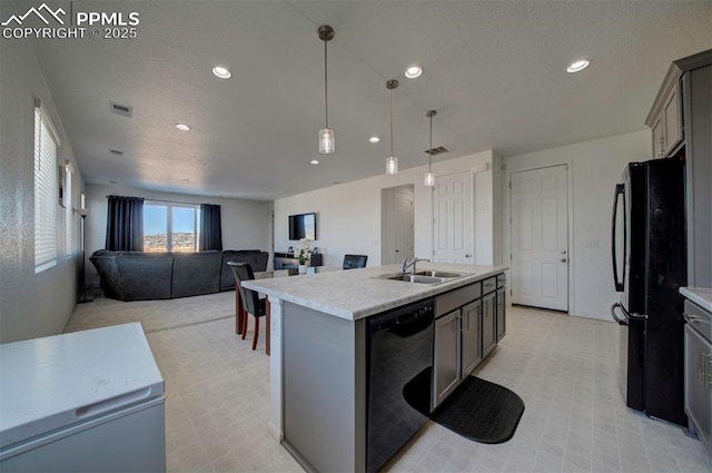 kitchen with sink, gray cabinetry, black appliances, an island with sink, and decorative light fixtures