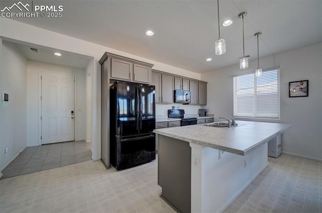 kitchen featuring a breakfast bar, sink, hanging light fixtures, an island with sink, and black appliances